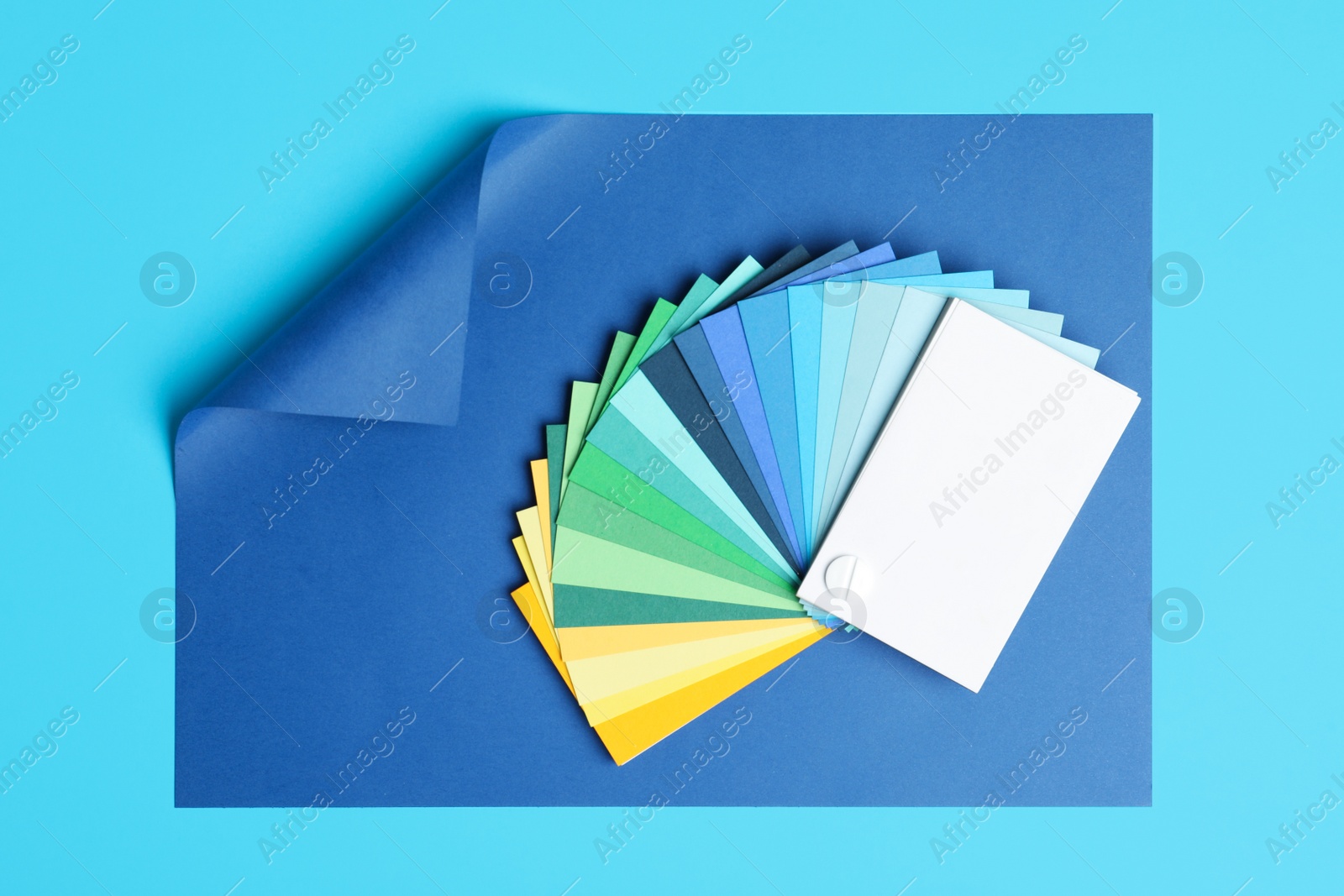 Photo of Color palette and bright paper on light blue background, top view