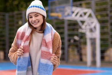 Photo of Beautiful woman in warm scarf and hat outdoors, space for text