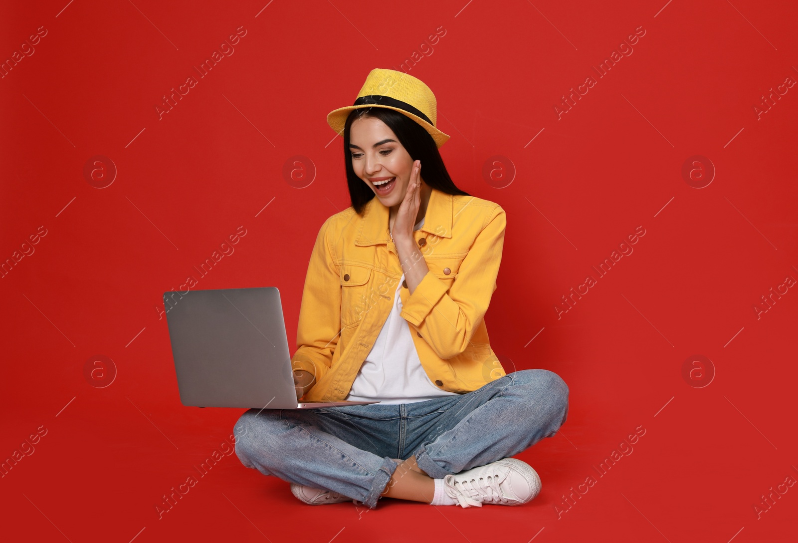 Photo of Emotional young woman with modern laptop on red background. Space for text