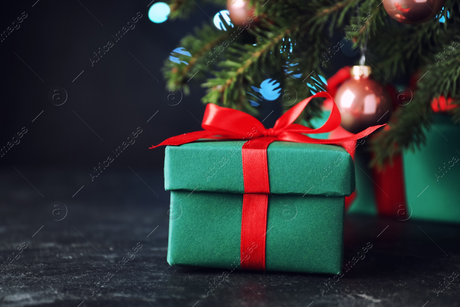 Photo of Gift boxes near Christmas tree on dark background, closeup