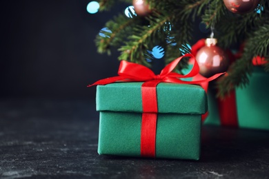 Photo of Gift boxes near Christmas tree on dark background, closeup