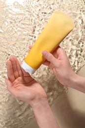 Photo of Woman applying face cleansing product onto hand against beige background, top view