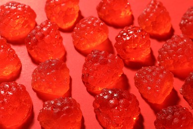 Photo of Delicious gummy raspberry candies on red background, closeup