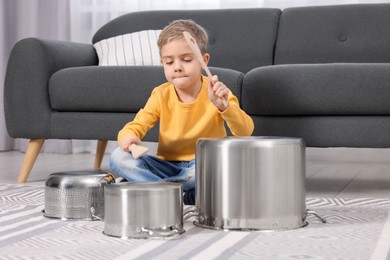 Little boy pretending to play drums on pots at home