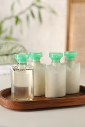 Photo of Mini bottles of cosmetic products on white table against blurred background