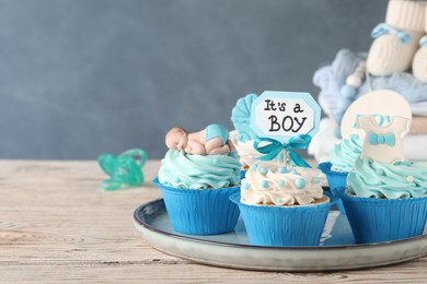 Photo of Beautifully decorated baby shower cupcakes for boy with cream on white wooden table. Space for text