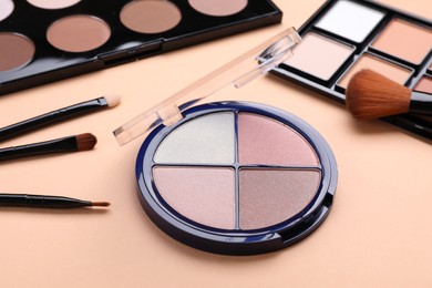 Colorful contouring palettes with brushes on beige background, closeup. Professional cosmetic product
