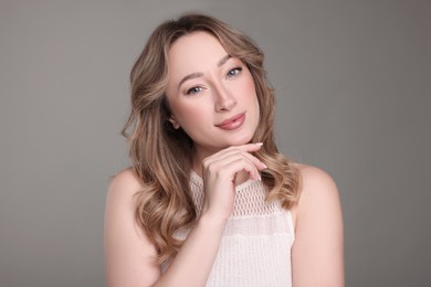 Portrait of beautiful woman with curly hair on grey background