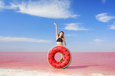 Photo of Beautiful woman with inflatable ring posing near pink lake on sunny day
