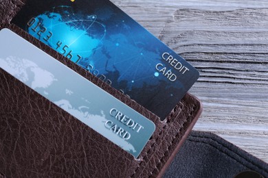 Photo of Credit cards in leather wallet on grey wooden table, top view
