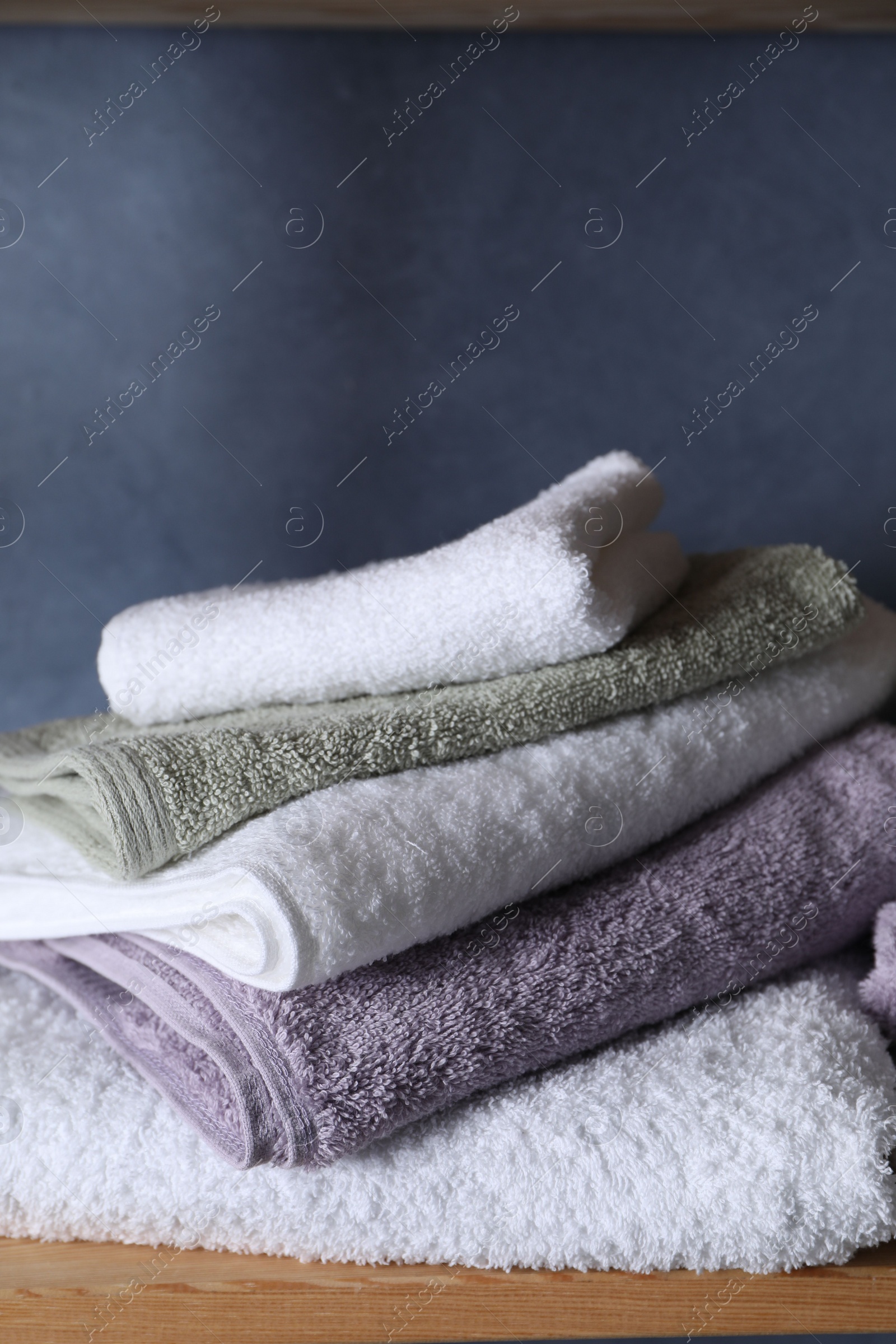 Photo of Stacked soft towels on wooden shelf indoors