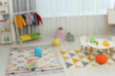 Photo of Blurred view of child`s playroom with different toys and furniture. Stylish kindergarten interior