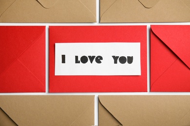 Card with phrase I Love You and envelopes on white background, flat lay