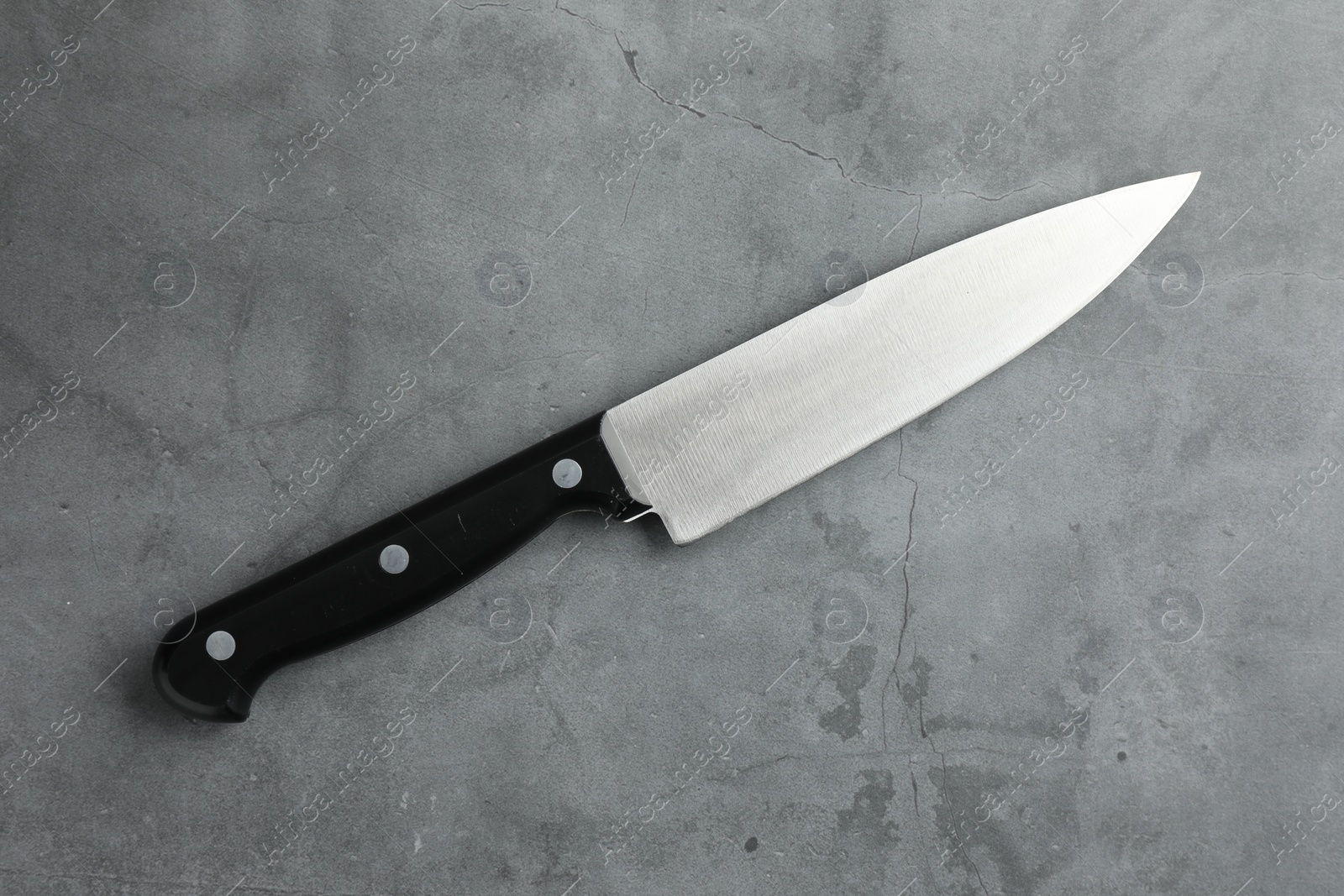 Photo of One knife on grey textured table, top view