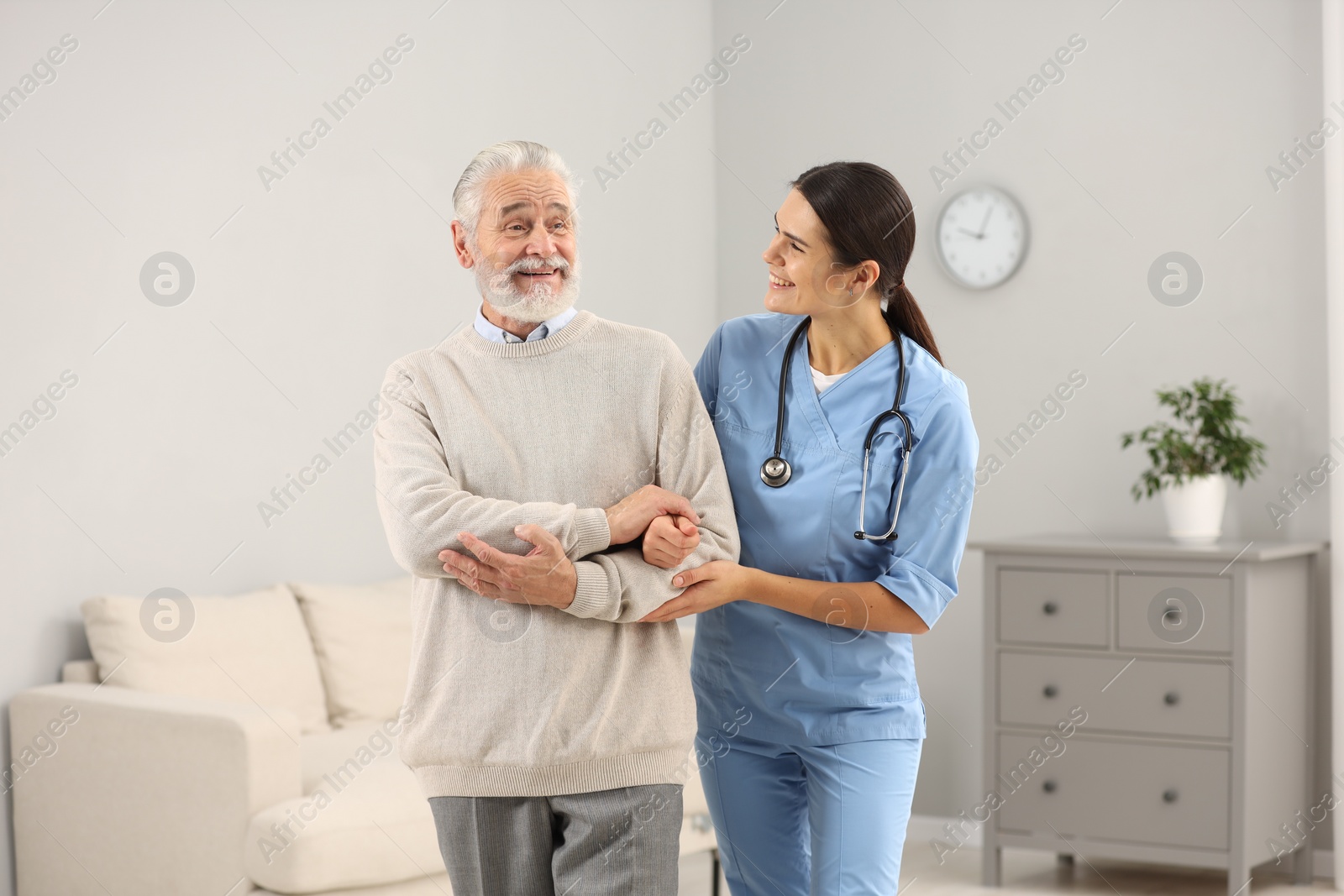 Photo of Smiling nurse supporting elderly patient in hospital