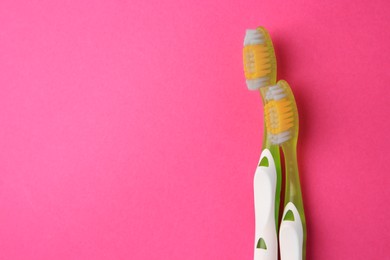 Photo of Toothbrushes on pink background. Space for text