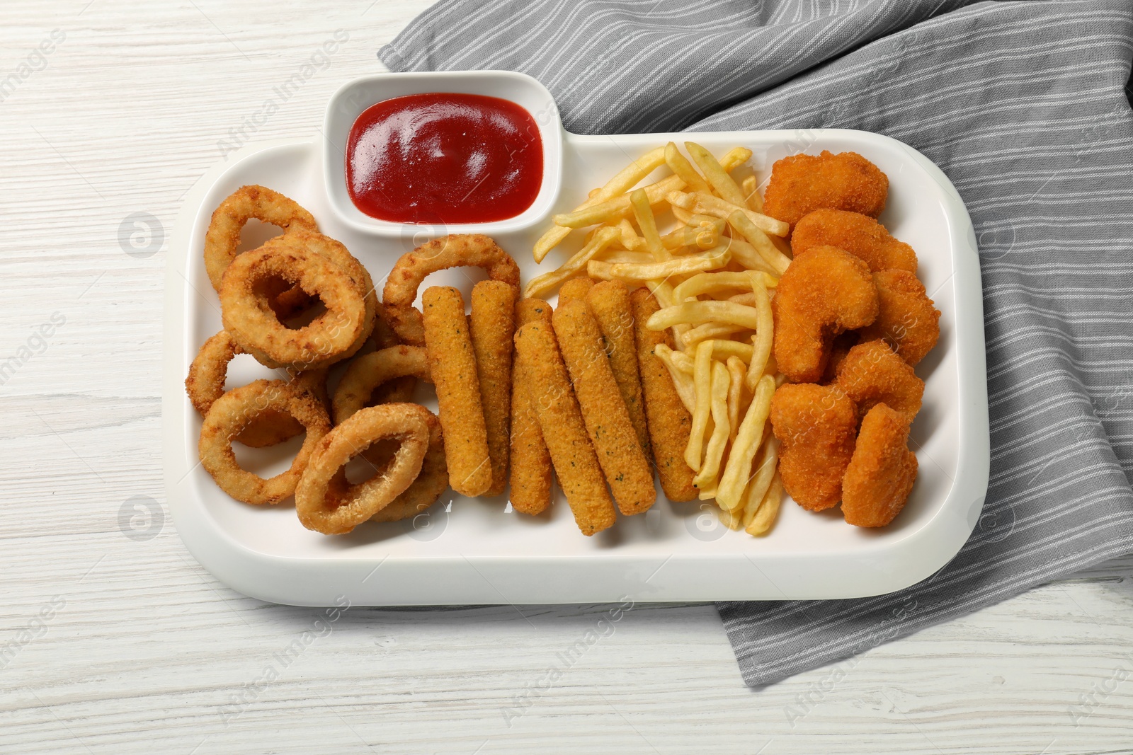 Photo of Tasty ketchup and different snacks on white wooden table, top view