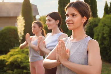 Photo of Young women practicing yoga outdoors on sunny day