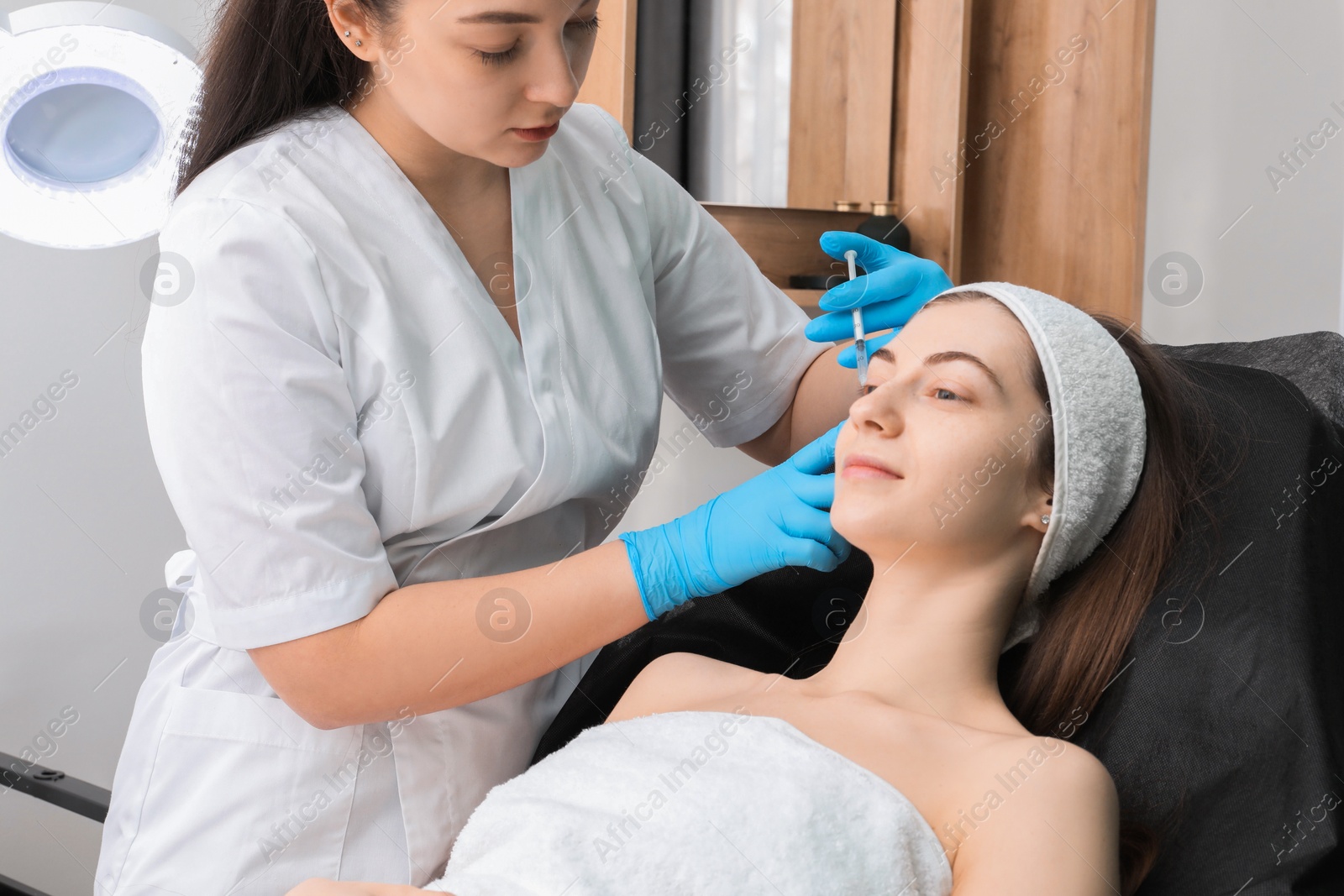 Photo of Cosmetologist giving facial injection to patient in clinic. Cosmetic surgery