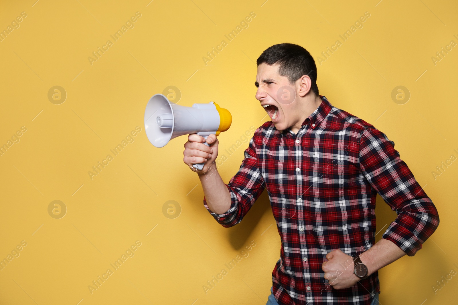 Photo of Portrait of young man using megaphone on color background. Space for text