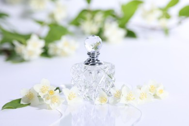 Photo of Aromatic perfume in bottle and beautiful jasmine flowers on white background