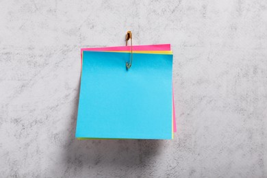 Photo of Colorful paper notes attached with safety pin on grey textured background, top view