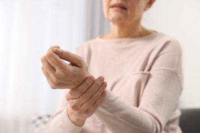 Photo of Arthritis symptoms. Woman suffering from pain in wrist at home, closeup