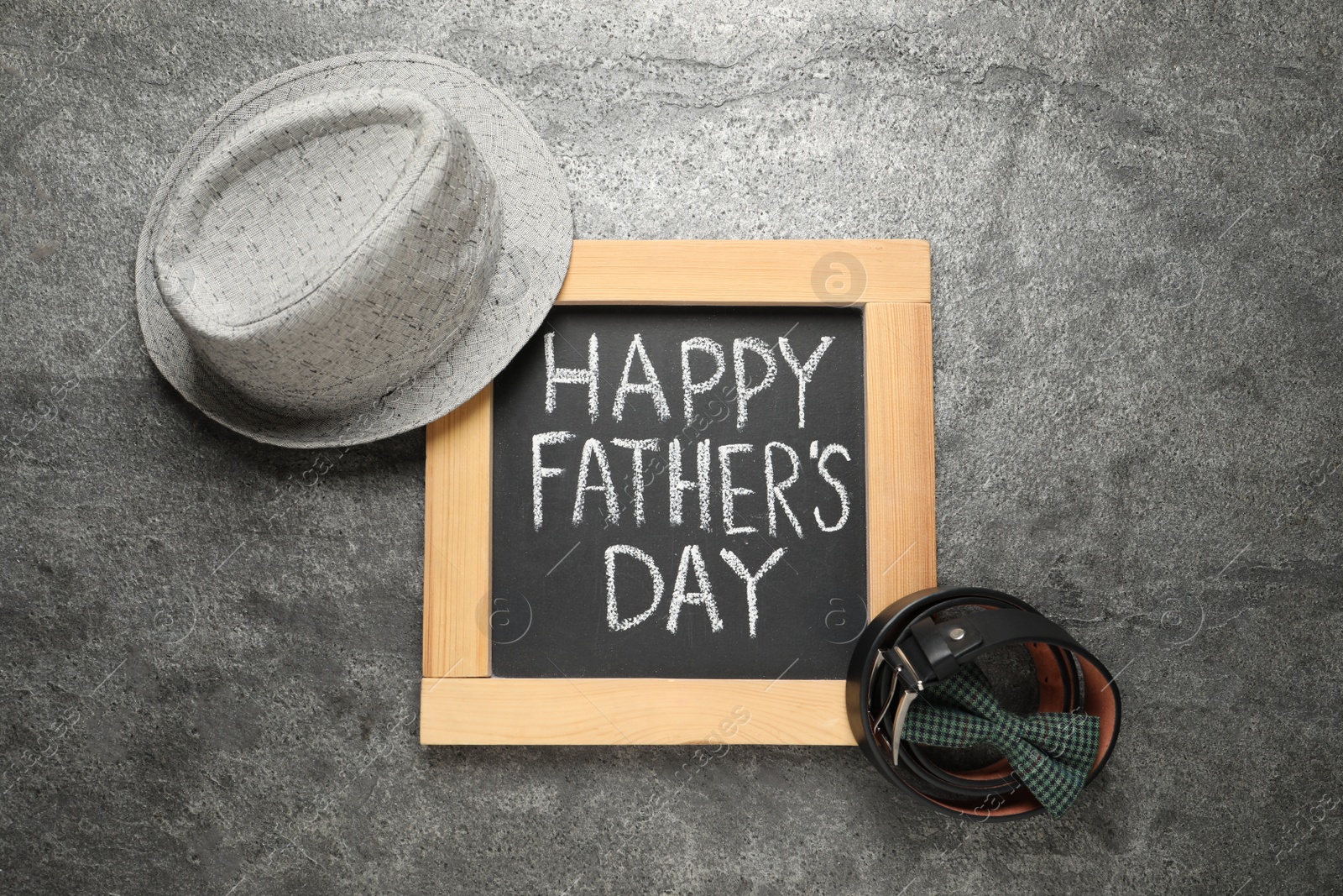 Photo of Chalkboard with phrase Happy Father's Day and men accessories on grey background, flat lay