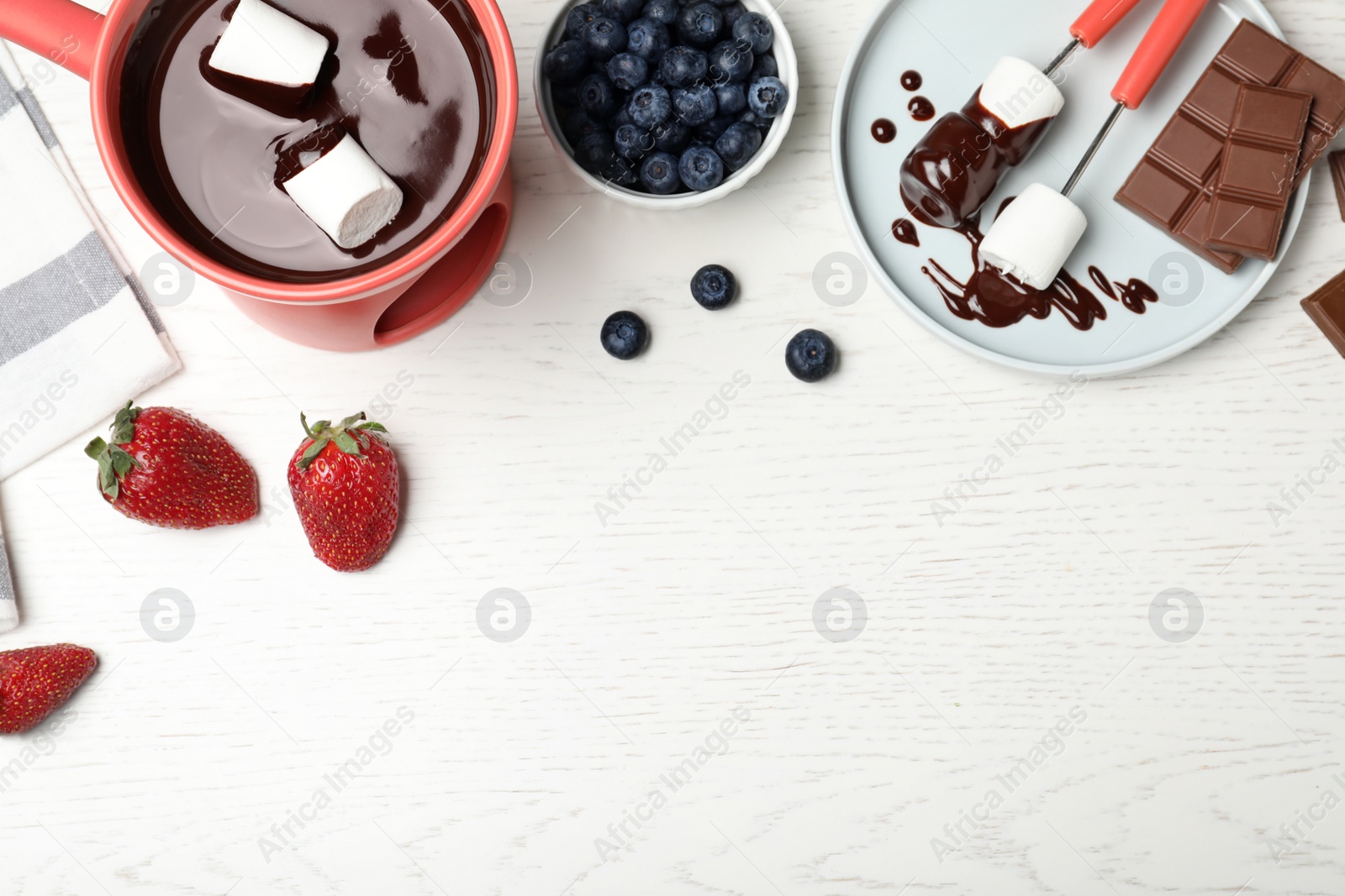 Photo of Chocolate fondue with strawberries and marshmallow on wooden table