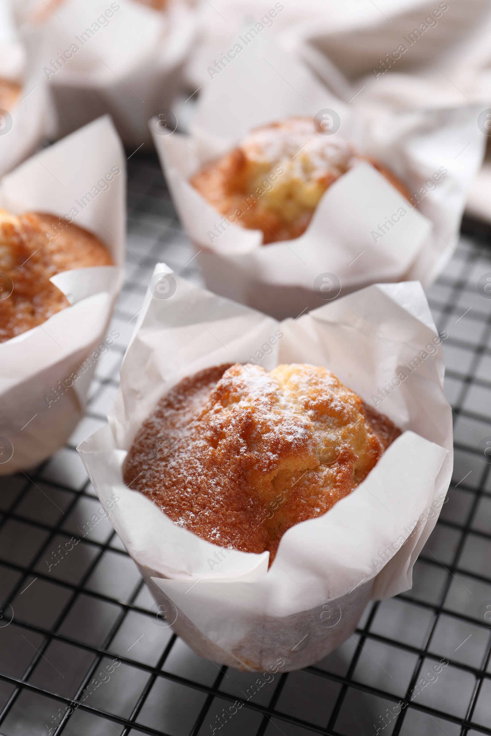 Photo of Delicious muffins with powdered sugar on light table, closeup