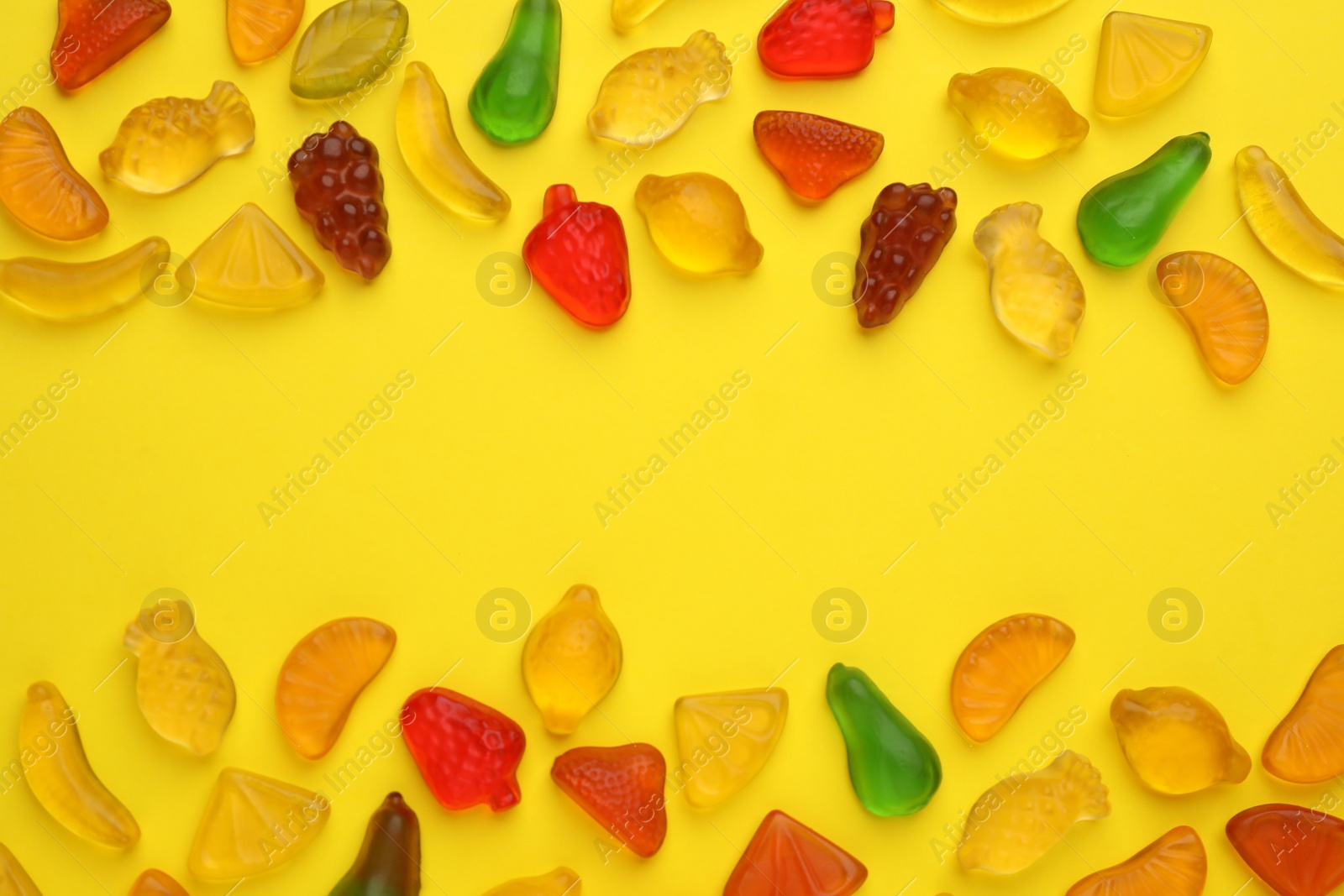 Photo of Tasty jelly candies in shape of different fruits on yellow background, flat lay. Space for text