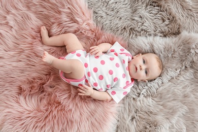 Cute little baby lying on soft fluffy plaid at home