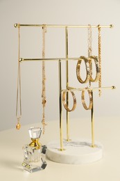 Photo of Holder with set of luxurious jewelry and perfume on white table