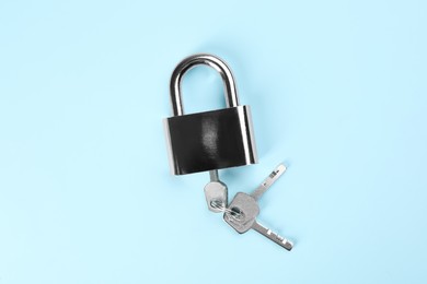 Photo of Modern padlock with keys on light blue background, top view