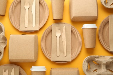 Photo of Paper and wooden tableware on yellow background, flat lay. Eco friendly lifestyle