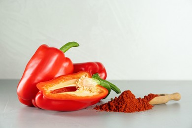 Photo of Fresh bell peppers and scoop of paprika powder on white table
