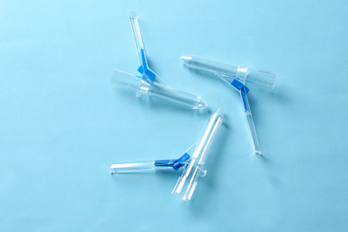 Photo of Anoscopes on light blue background, flat lay. Hemorrhoid treatment