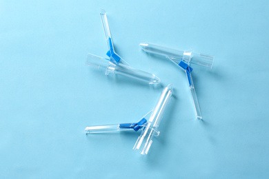 Anoscopes on light blue background, flat lay. Hemorrhoid treatment