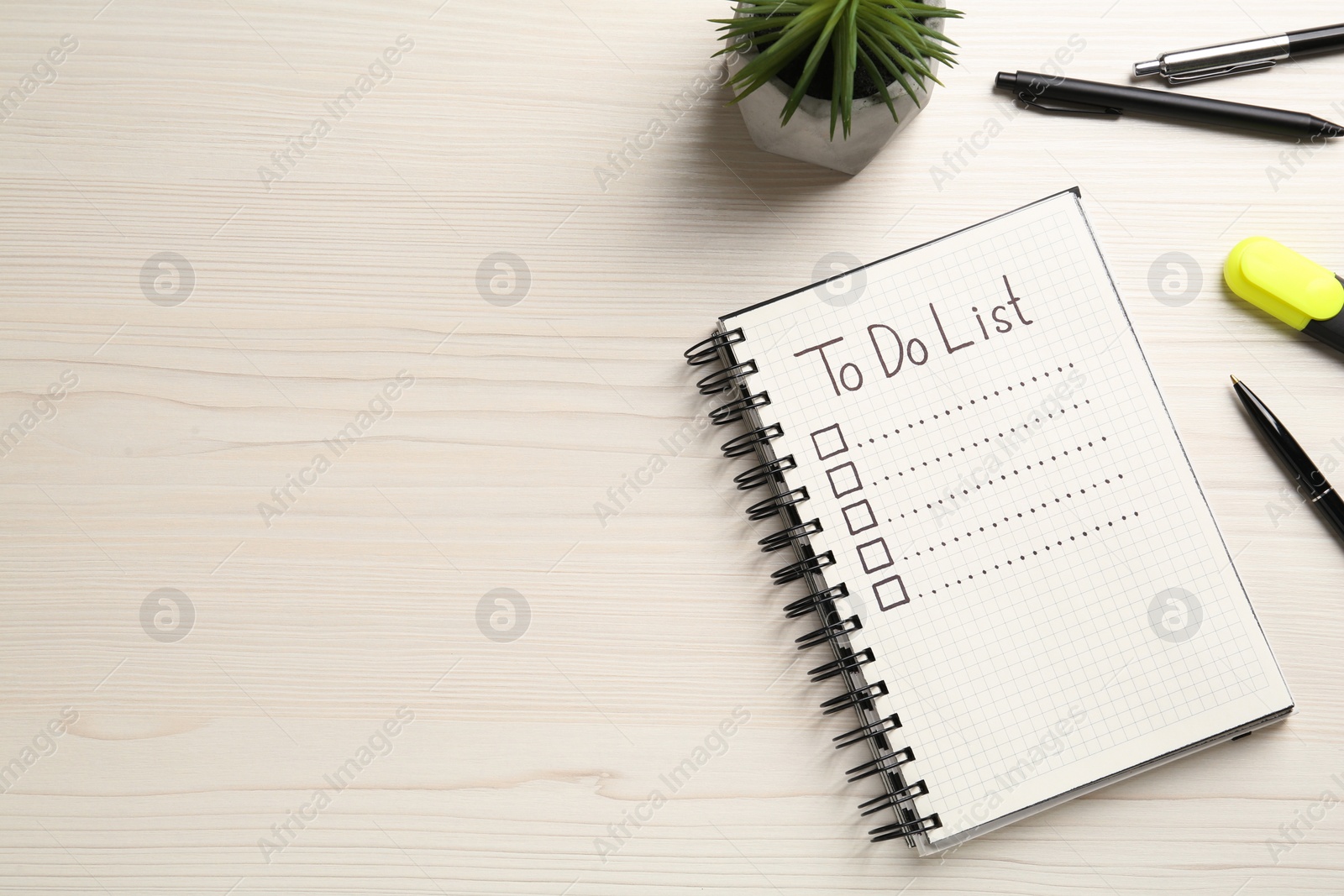 Photo of Notepad with unfilled To Do list, pens and houseplant on wooden table, flat lay. Space for text