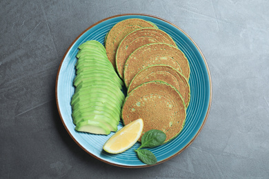 Tasty spinach pancakes served on grey table, top view