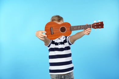 Photo of Little boy showing guitar on color background