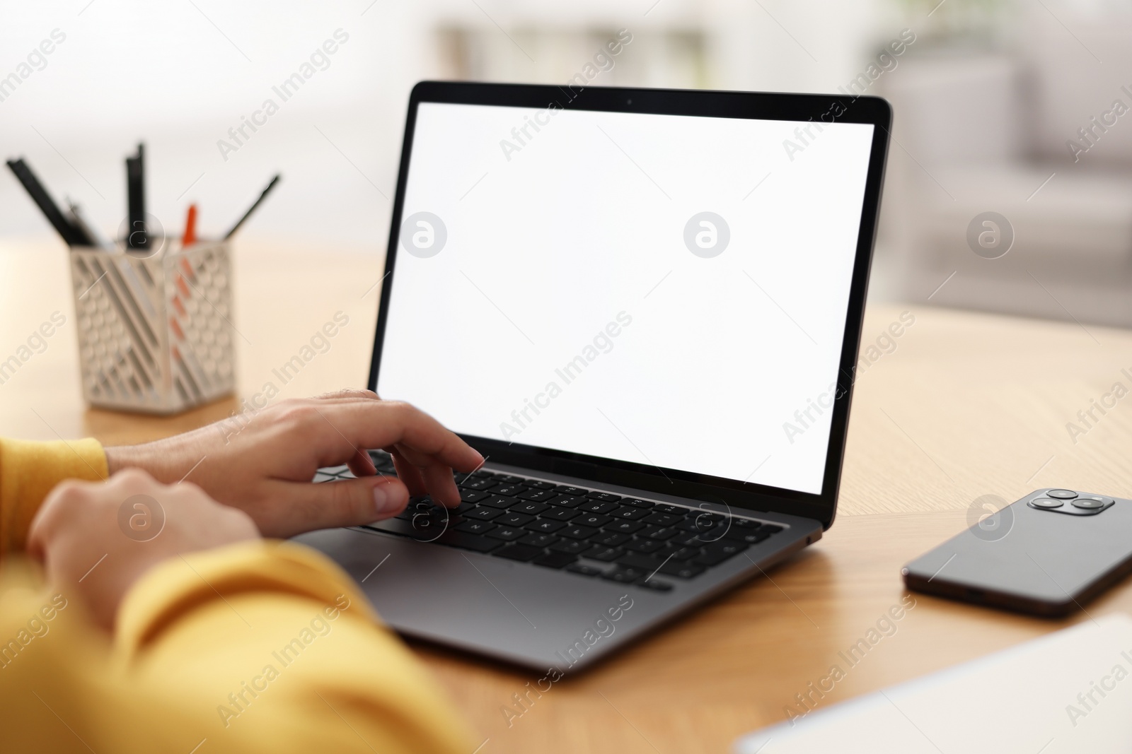 Photo of Young man watching webinar at table indoors, closeup