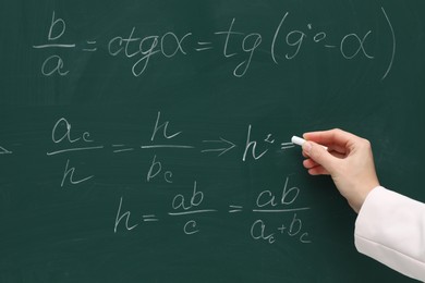 Teacher writing down math equation on green board, closeup