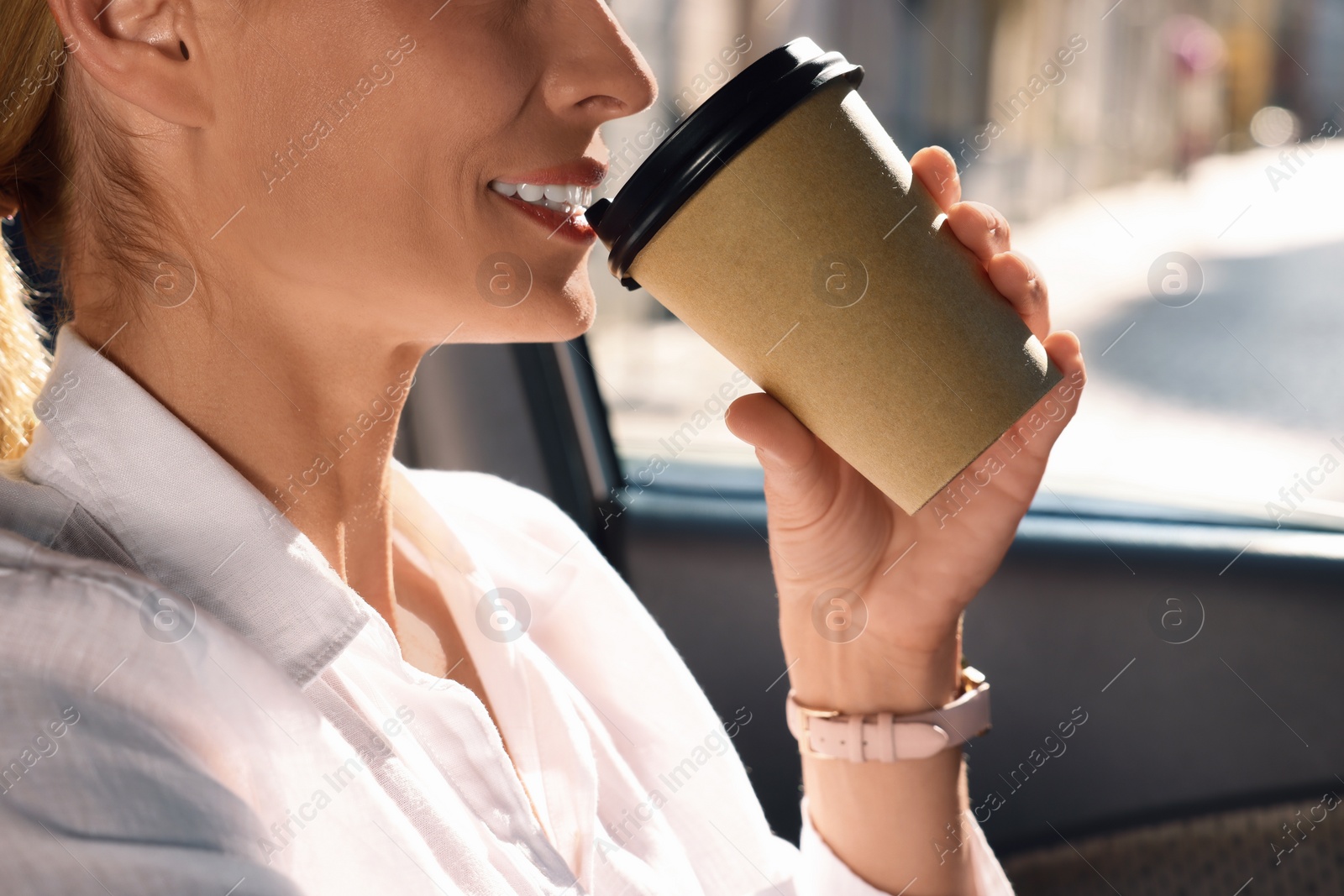 Photo of To-go drink. Woman drinking coffee in car, closeup