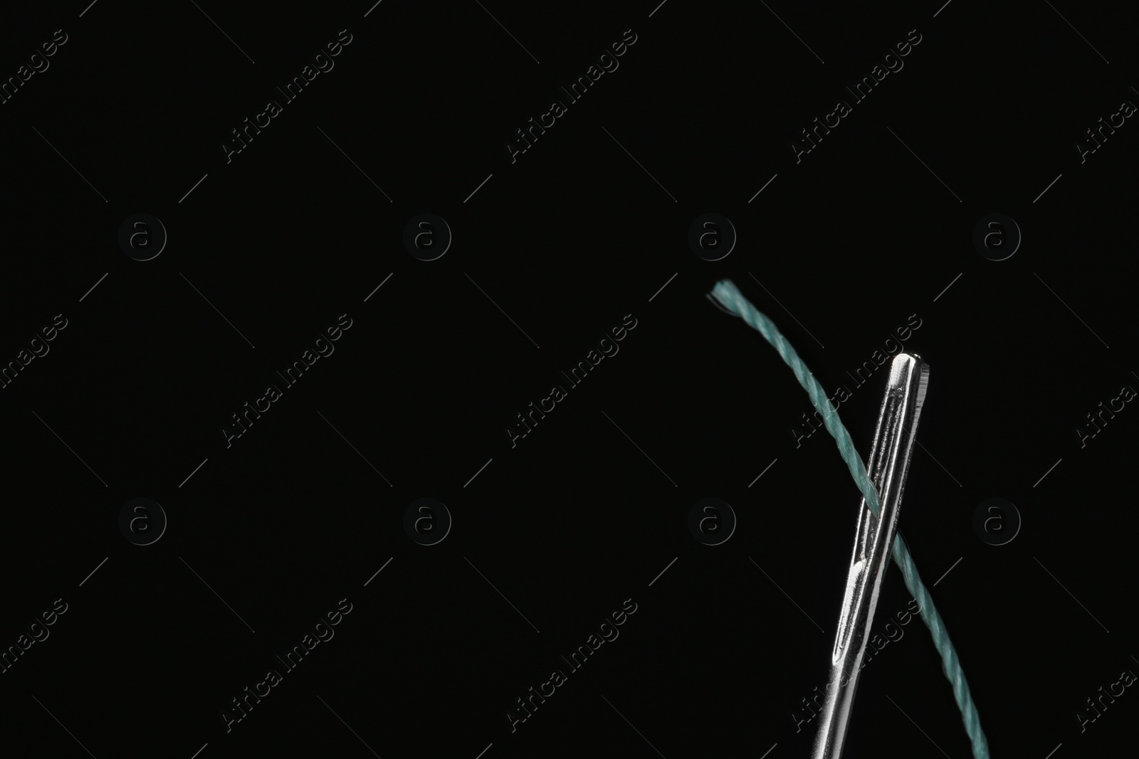 Photo of Needle with sewing thread on black background, closeup