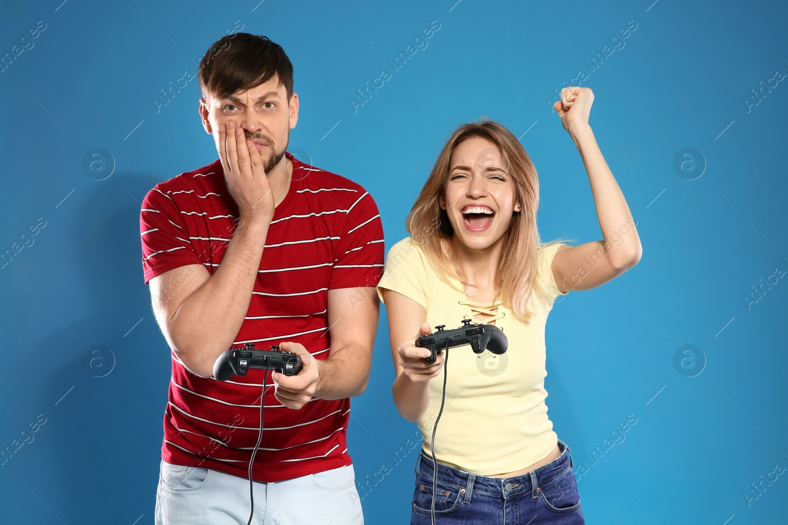 Photo of Emotional couple playing video games with controllers on color background