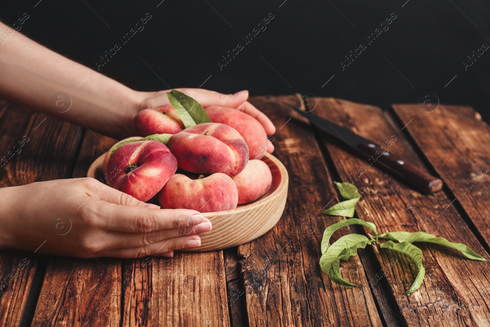 Photo of Woman with fresh donut peaches at wooden table, closeup