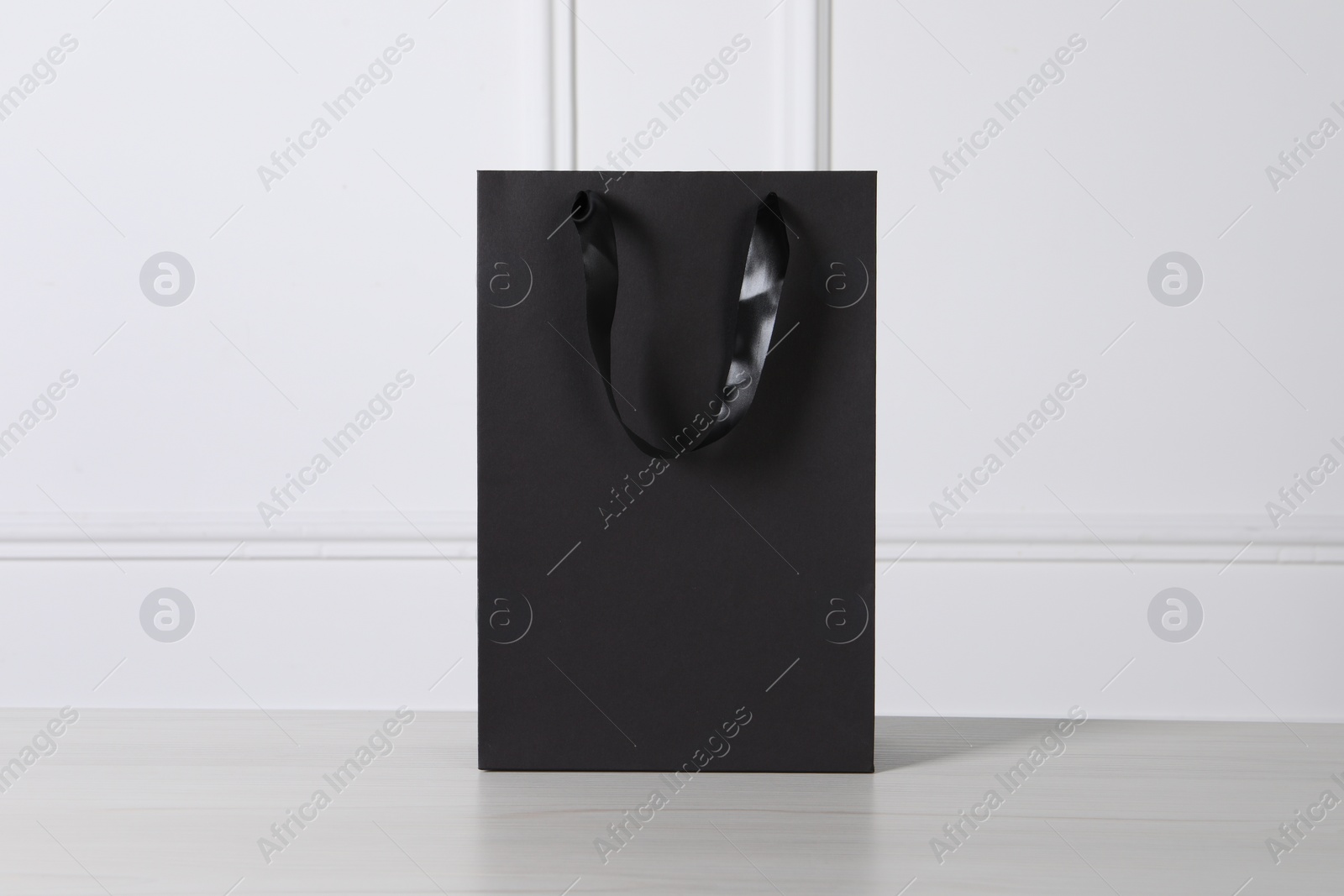 Photo of Black paper bag on white wooden table