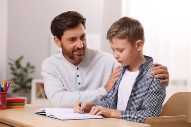Dyslexia problem. Father helping son with homework at table in room