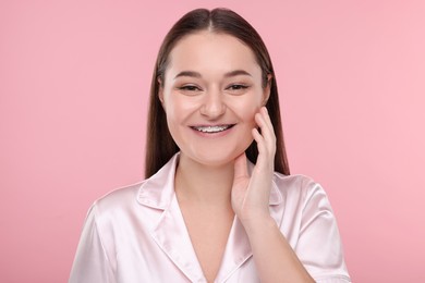 Smiling woman with dental braces on pink background